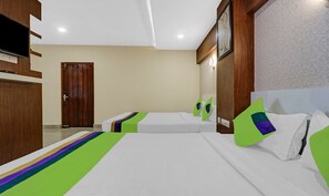 Quarto de hotel com duas camas, televisão e porta de madeira.