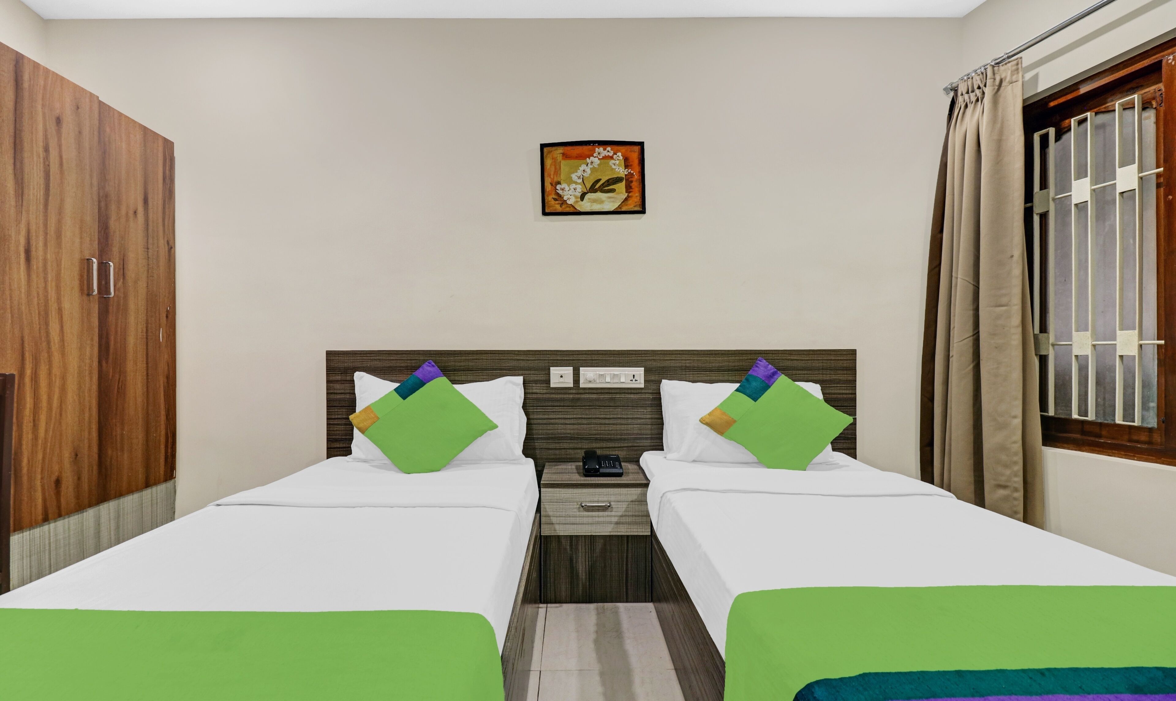 A hotel room with two beds, a nightstand, a wall-mounted painting, and a window with curtains.