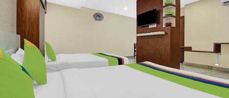 Habitación de hotel con dos camas, televisión, ventilador y pared con paneles de madera.
