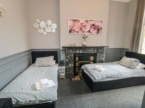 A double room with two beds, a fireplace, and a floral wall decoration.