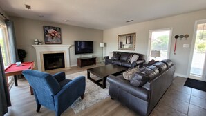 A living room with a fireplace, a television, a sofa, and a pool table. - Beautiful 3 bedroom Sports Village Condo--sleeps 10. (St. George)