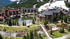 Una località montana con un lago, edifici e una pista da sci.