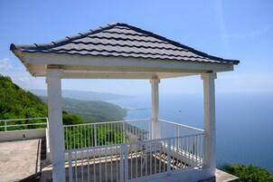 Una pérgola con techo de tejas que da a un paisaje costero.