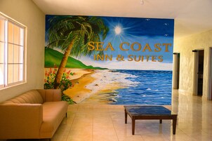 Una habitación con un mural de una playa, un sofá y una mesa.