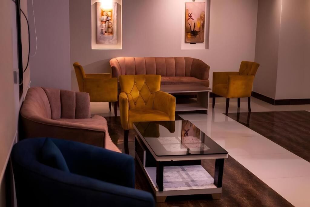 A modern living room with a brown sofa, yellow armchairs, and a glass coffee table.