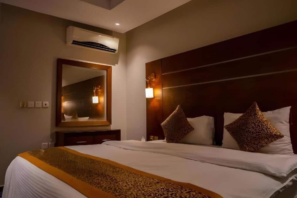 Quarto de hotel com uma cama grande, um espelho, ar condicionado e uma mesa de cabeceira.