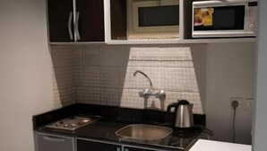 A compact kitchen with a stove, sink, and microwave. - Ahlin 2 Serviced Apartment (Riyadh)