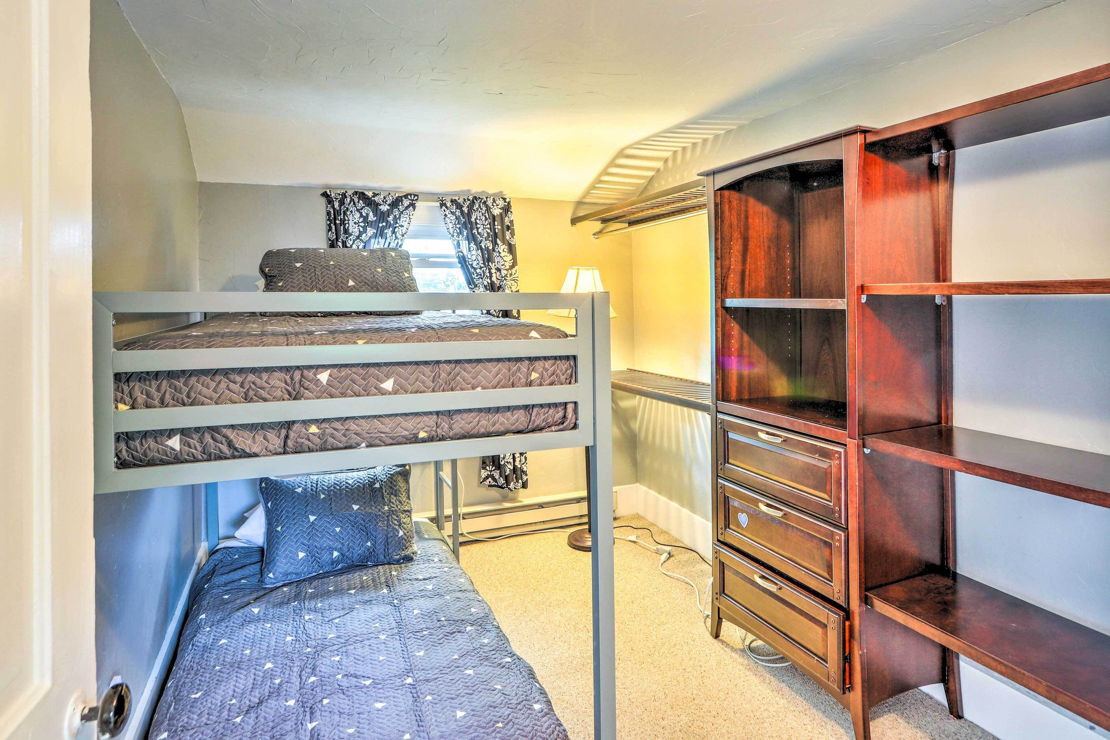 Une chambre avec un lit superposé, une commode en bois et un radiateur.