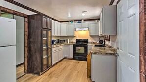 Una cocina compacta con armarios blancos, una estufa negra y un microondas.