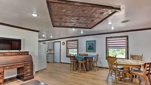 Un comedor amplio con una mesa y sillas de madera, una cocina al fondo y un techo decorativo.