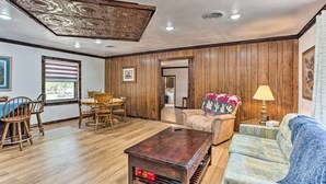 Una sala de estar con paneles de madera, una zona de comedor con mesa y sillas, y un sofá con una manta.
