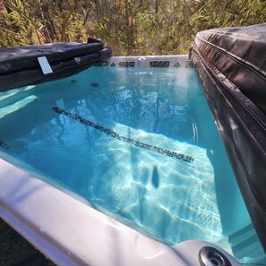 A clear swimming pool with a tiled deck and a lounge area.