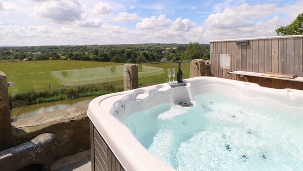 A hot tub with a view of a golf course and a wooden deck. - Low Shipley Mill (Barnard Castle)