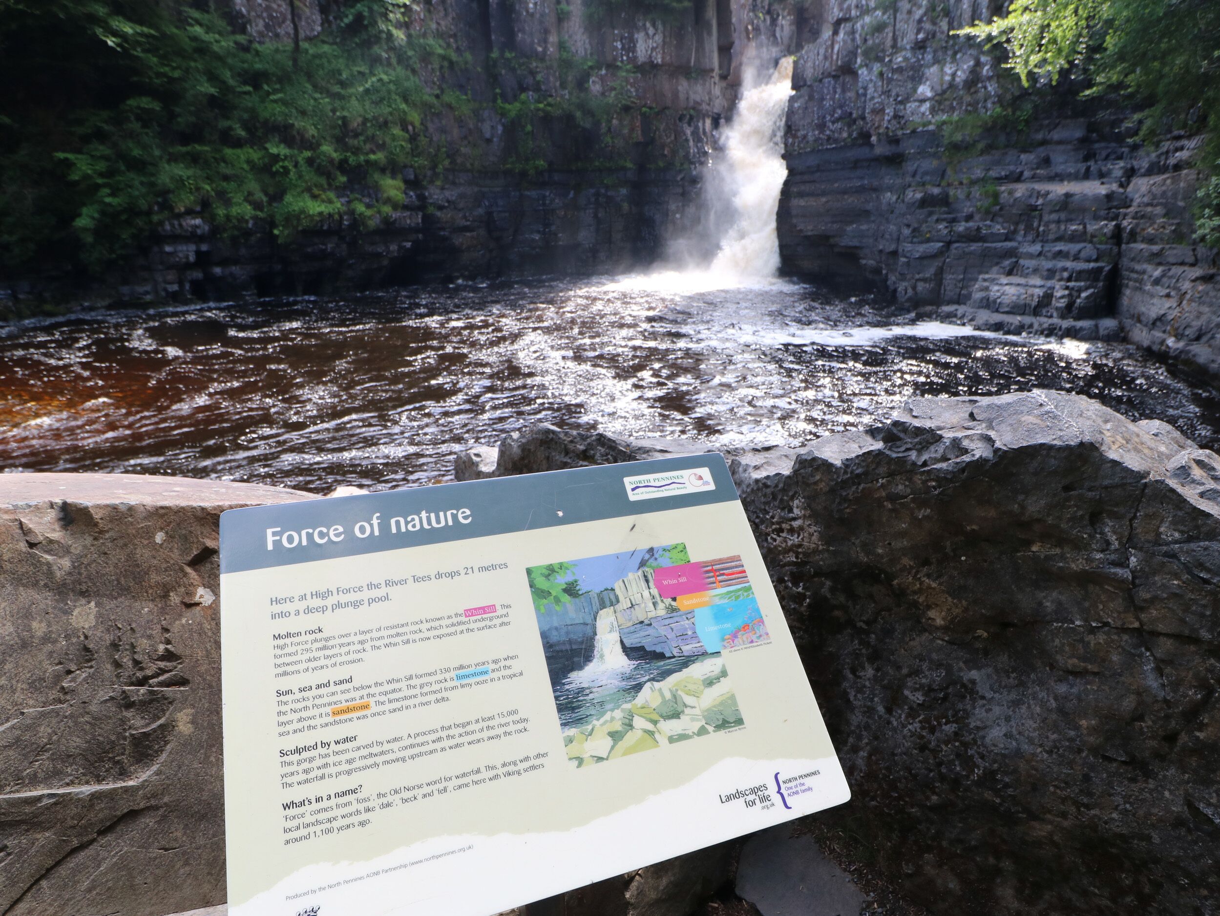 A waterfall with a sign titled "Force of Nature" describing geological features.