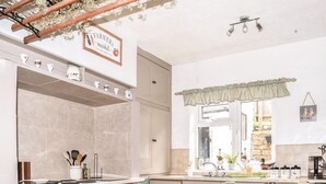 Una cocina con estufa, horno y lavaplatos, una ventana con vistas, y un cartel sobre la estufa.