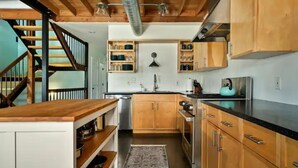 Une cuisine avec des meubles de rangement en bois, un plan de travail noir et un évier en acier inoxydable.