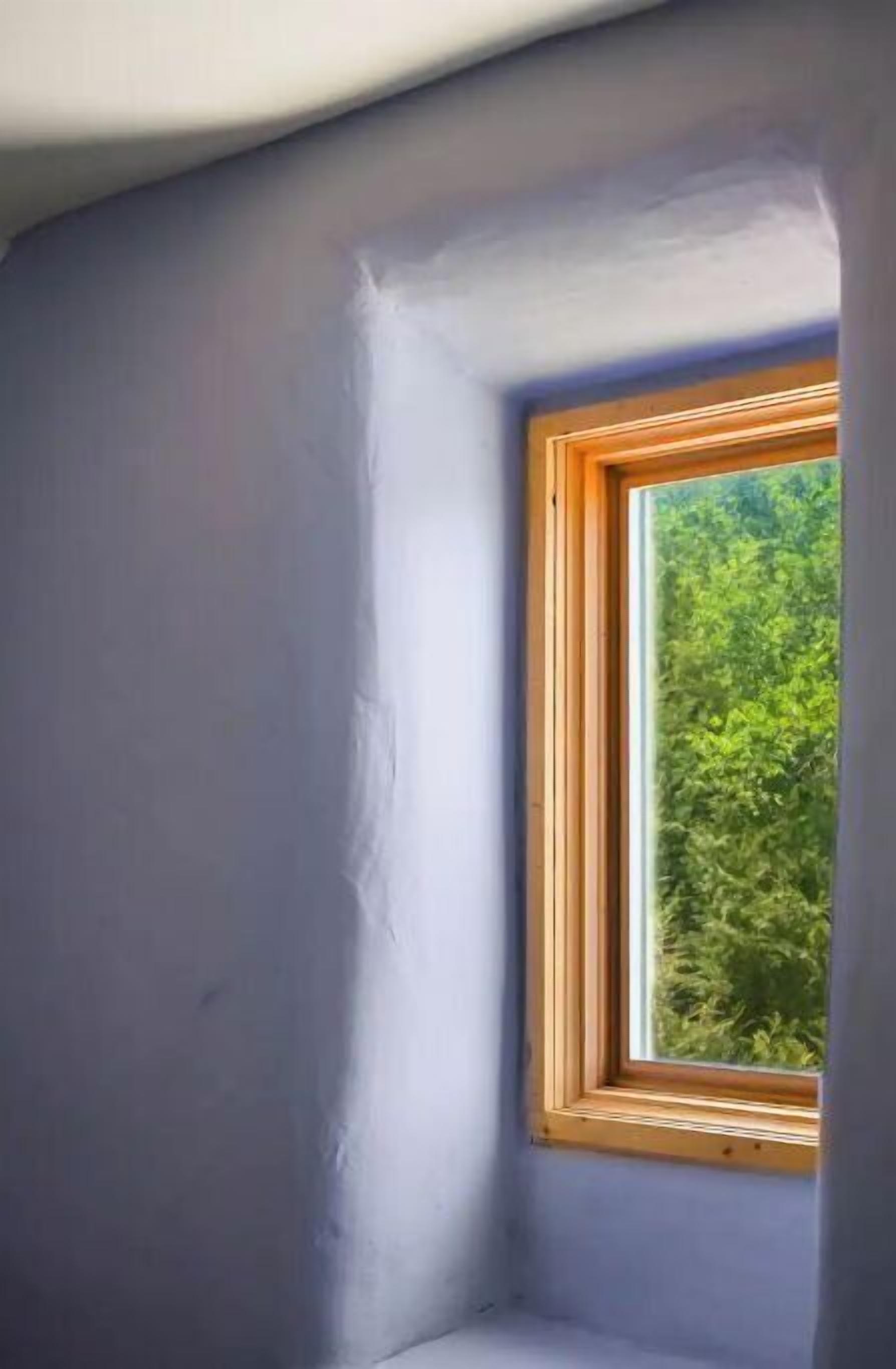 Une petite pièce fermée, avec une seule fenêtre, un plafond en pente et un mur uni.