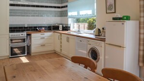 A compact kitchen with white cabinets, a microwave, a dishwasher, and a washing machine. - 2 bedroom accommodation in Thorpe St Peter (Thorpe St Peter)