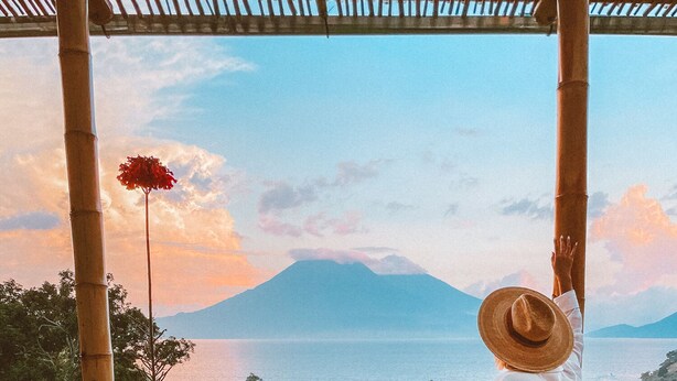A person standing on a balcony with a view of a mountain and a body of water. - Stunning Luxury Eco Villa (Tzununa)