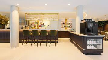 A modern bar area with a counter, bar stools, and a coffee machine.