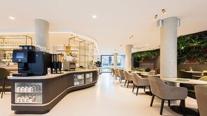 Una cafetería moderna con mostrador curvo, zona de estar y vistas al exterior.