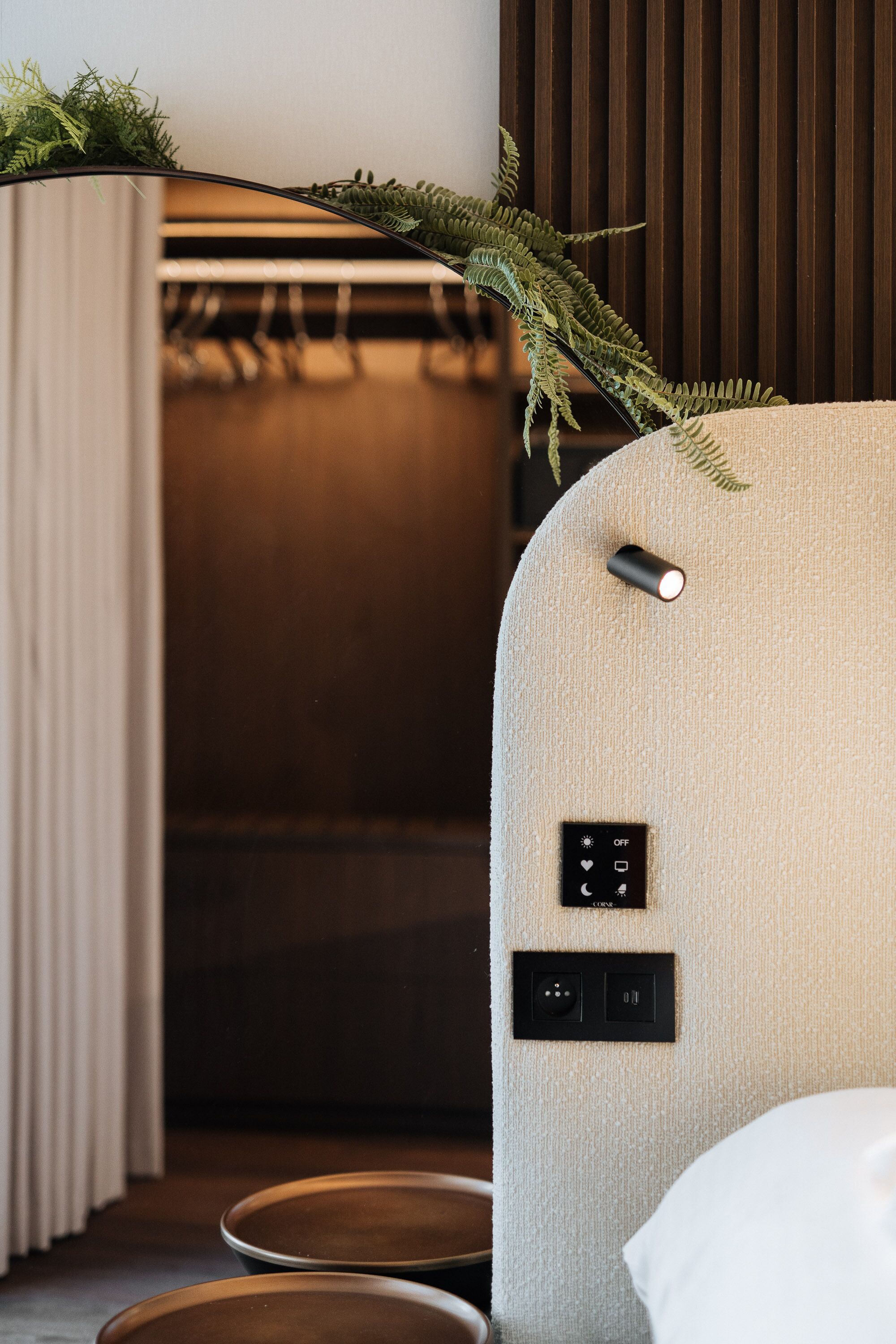 A modern room with a textured wall, a bed with a white pillow, and a control panel with buttons.