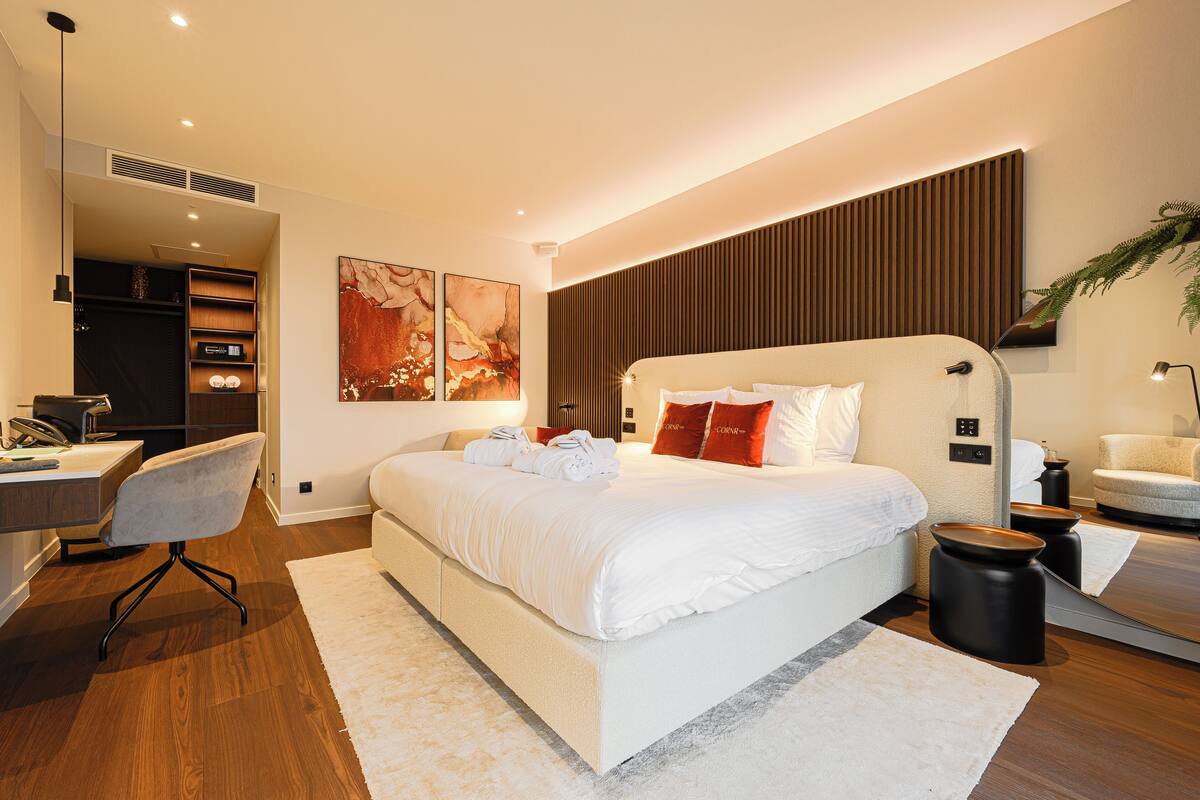 A modern hotel room with a large bed, a desk, and a chair.