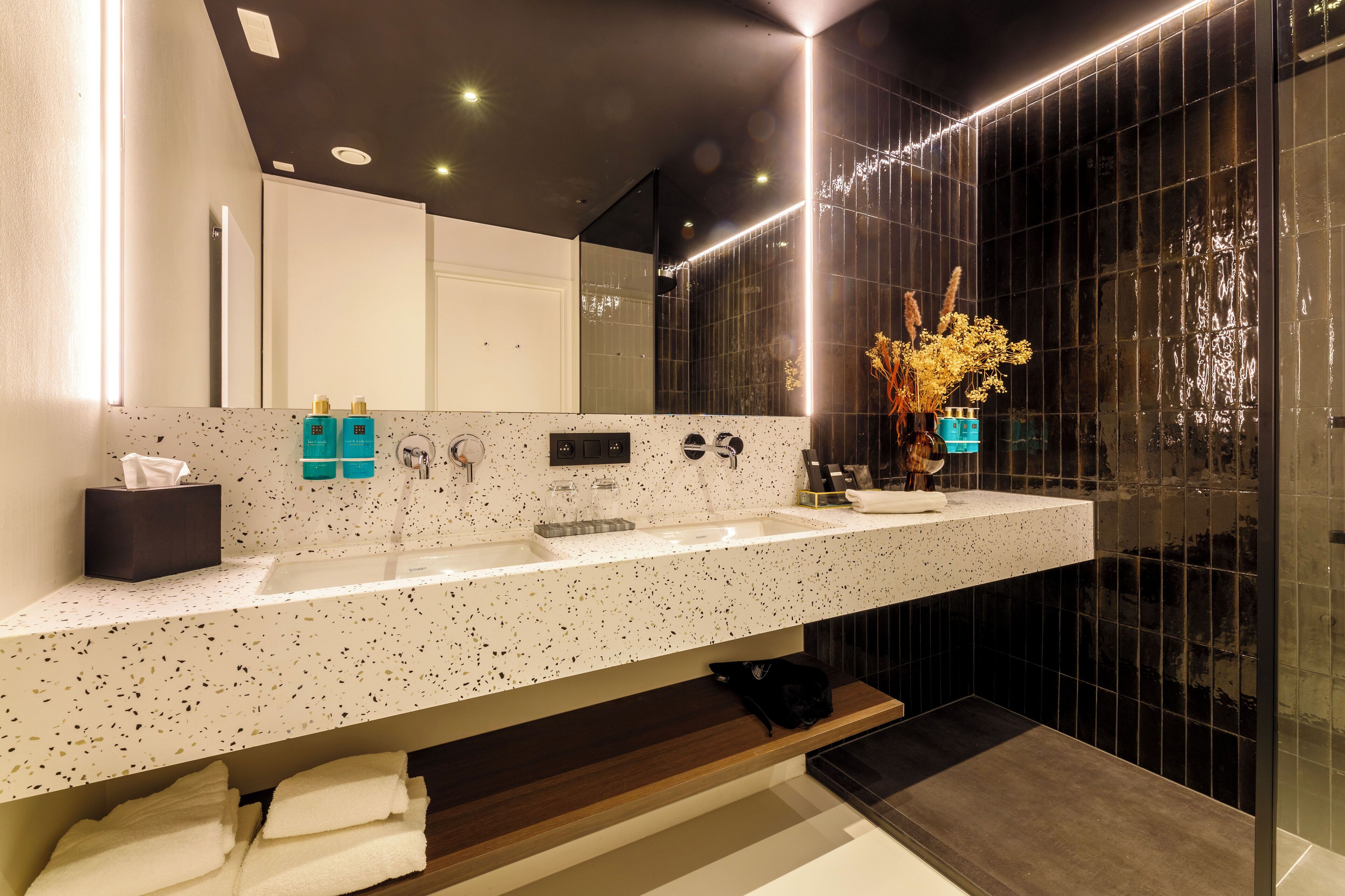 Un baño moderno con un espejo grande, dos lavamanos y una zona de tocador.