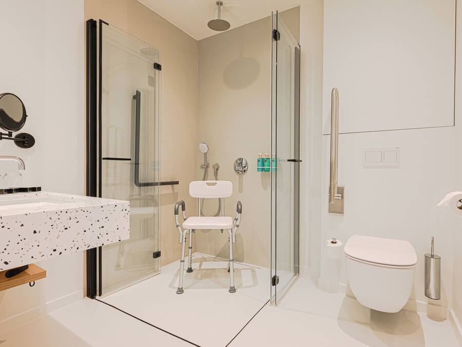Un baño moderno con cabina de ducha de vidrio, inodoro blanco y lavamanos con encimera de aspecto moteado.