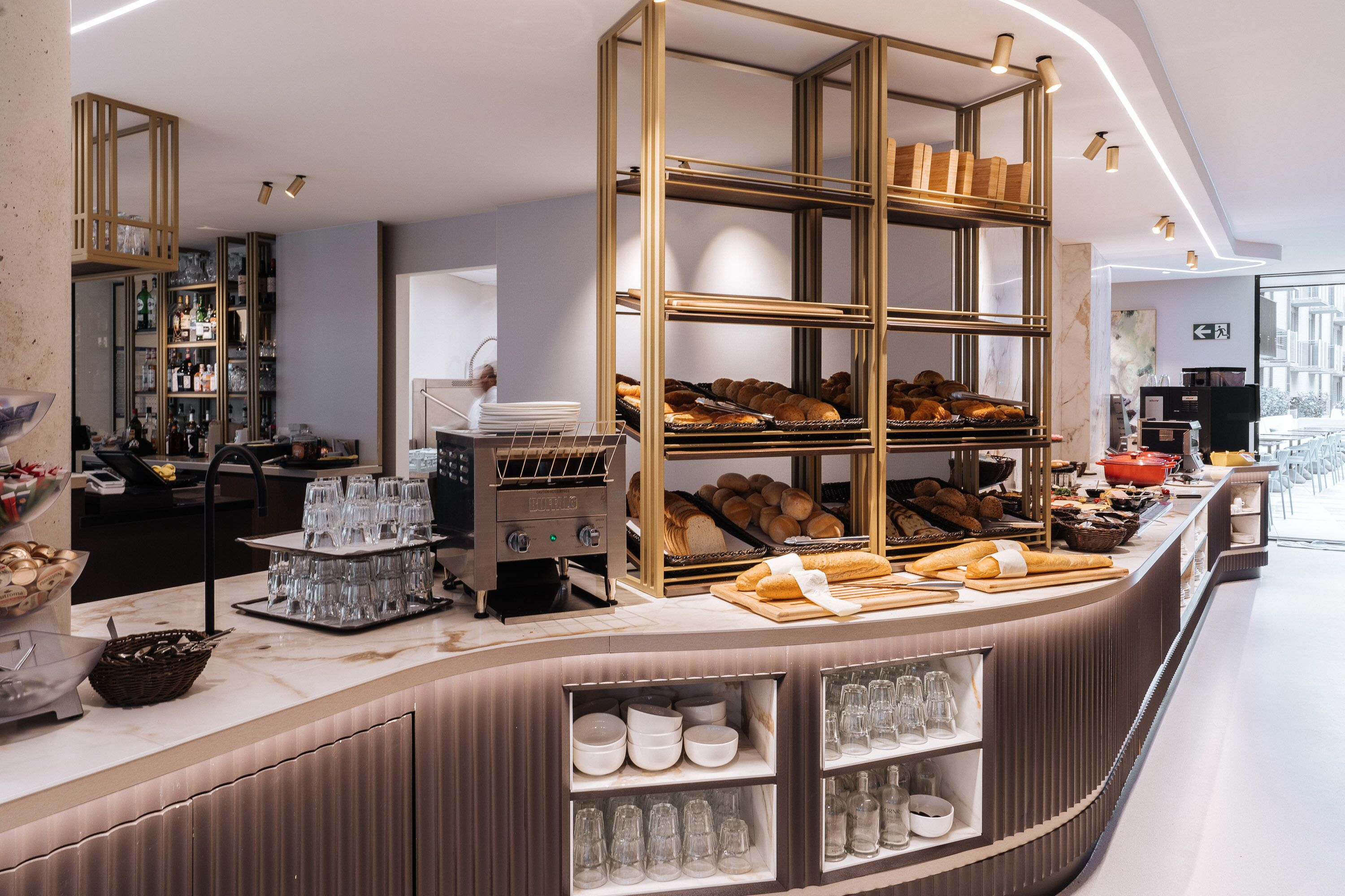 Een ontbijtbuffet met brood, gebak en een koffieapparaat.