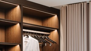 Un vestidor con estantes de madera, una bata colgada en un perchero y un microondas en el estante.