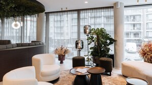 Un área de estar moderna con un sofá curvo, sillones blancos y una mesa de centro redonda.