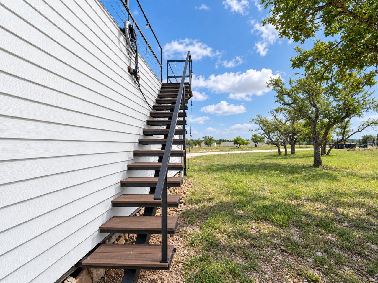 A wooden exterior staircase leading up to a white building with a metal railing.