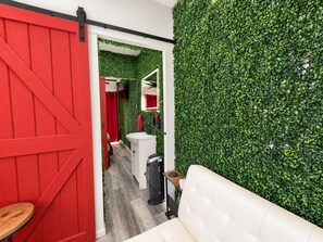 Een kamer met een rode schuurdeur, een witte bank en een groene muur.