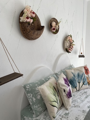 Quarto com cama, almofadas e decorações na parede.
