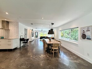 A spacious kitchen with a dining area, a black chair, and a table with a vase. - Heated pool-2 streets from beach-downtown-4 bedroom-3bath (Fort Lauderdale)
