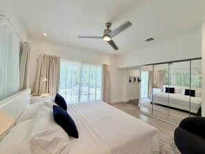 A modern bedroom with a large bed, a ceiling fan, and a view of a balcony. - Heated pool-2 streets from beach-downtown-4 bedroom-3bath (Fort Lauderdale)