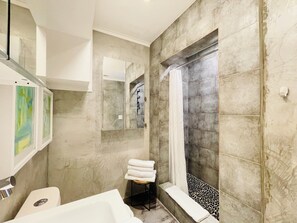 A modern bathroom with a bathtub, a shower, and a toilet.