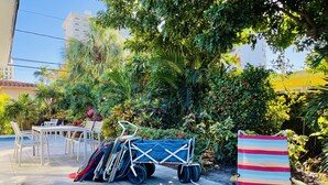 Un espace patio avec une table et des chaises, un chariot couvert et une chaise de plage à rayures.