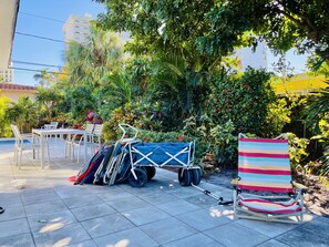 A patio area with a table and chairs, a covered cart, and a striped beach chair.
