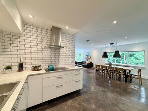 A modern kitchen with white cabinetry, a stainless steel sink, and a teal kettle on the counter.