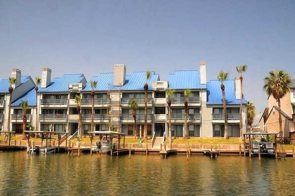 A multi-story hotel with blue roofs and balconies, located near a body of water. - Cozy Beach Retreat with Canal Access! (Corpus Christi)