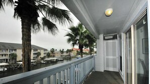Un balcon avec vue sur un port de plaisance, des palmiers et des bâtiments en arrière-plan.