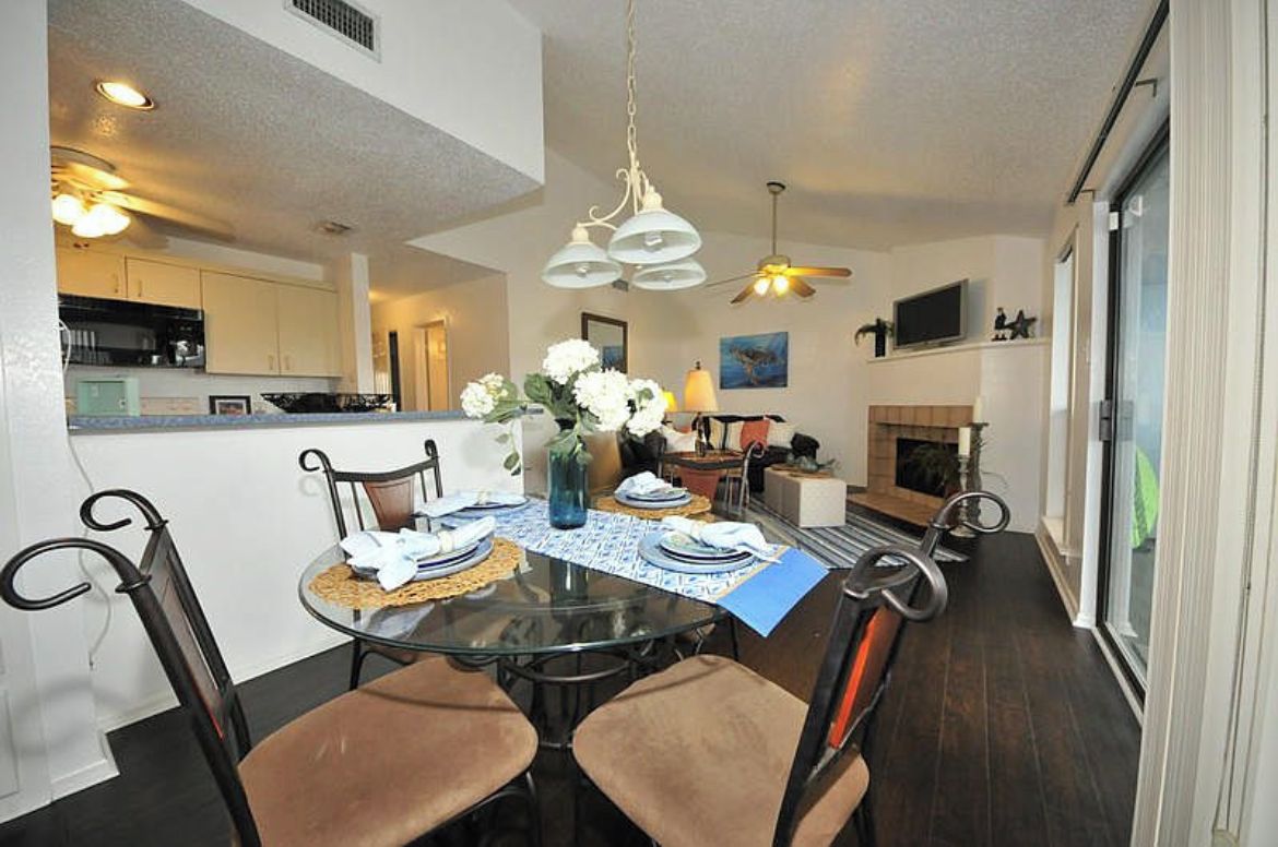 A dining area with a round glass table, four chairs, and a chandelier.