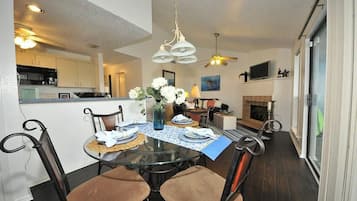 A dining area with a round glass table, four chairs, and a chandelier.