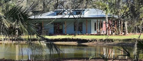 A house with a blue roof, surrounded by trees and a pond.
