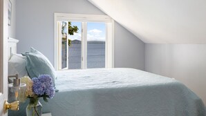 A bedroom with a large window offering a view of a lake and mountains. - Tranquil lake house in VT w/ breathtaking views! (Grand Isle)