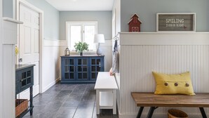A hallway with a blue cabinet, a white bench, and a yellow pillow. - Tranquil lake house in VT w/ breathtaking views! (Grand Isle)