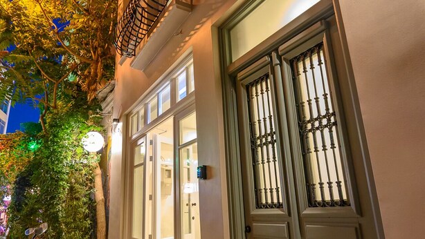 A building with a large, ornate gate, a staircase with a metal railing, and a tree with green leaves. - Belle Athenes - Luxury Rooms at Monastiraki Railway Station (Athens)