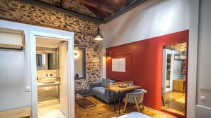 A modern bedroom with a wooden floor, a bed, a desk, and a chair. There is a bathroom visible through an open door. - Belle Athenes - Luxury Rooms at Monastiraki Railway Station (Athens)